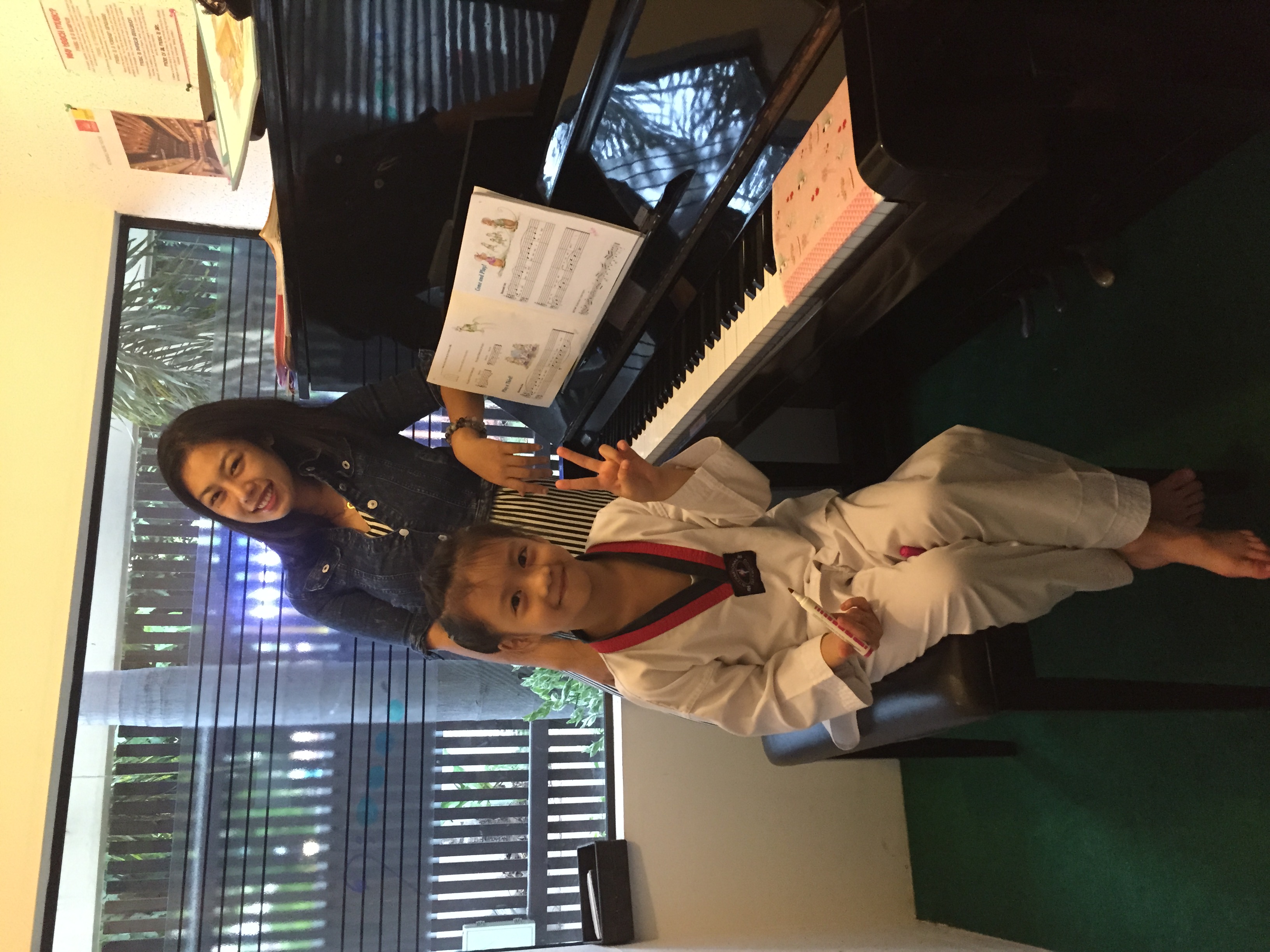 Minnie smiling with a young piano student beside a piano